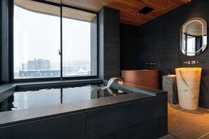 Une salle de bain moderne dotée d’une grande fenêtre, d’une baignoire et d’un lavabo en marbre.