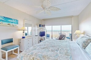 A bedroom with a bed, a desk, a chair, a bookshelf, and a balcony with a view. - Gulf-Front 2BR w/ Balcony: Suntide III - Unit 502 (South Padre Island)