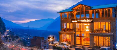 Un hotel con un cartello che recita 'Moustache Select' e una vista sulle montagne sullo sfondo.
