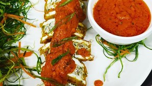 A dish of breaded chicken cutlets with a red sauce, served with a side of greens and a bowl of sauce. - STUDIO BY JARDIN  (Indore)