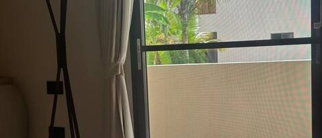 A hotel room with a bed, white towels, a window with a view of palm trees and buildings.