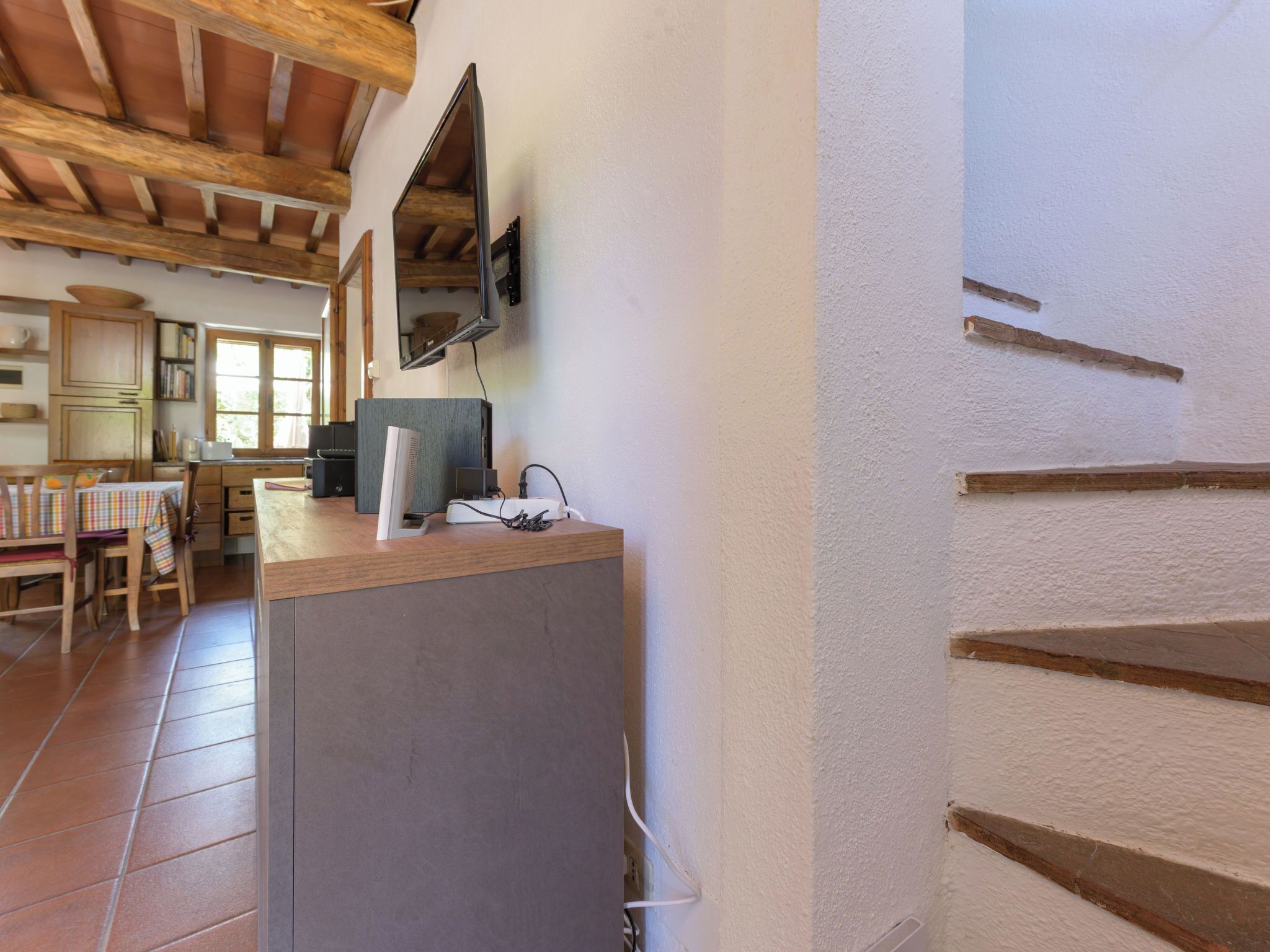 Une cuisine avec des poutres en bois, un coin repas avec une table et des chaises, et un escalier.