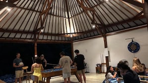 Zona recreativa interior con mesa de billar, dardos y asientos.