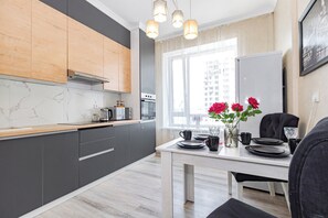 Une cuisine moderne avec des meubles gris, un plan de travail en bois et un coin repas avec une table dressée pour deux personnes.