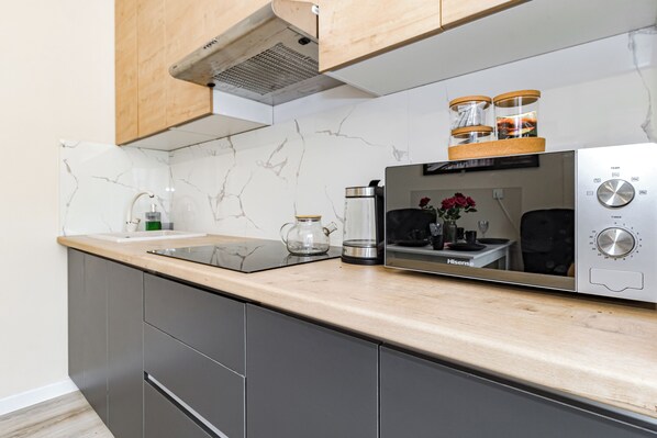 A modern kitchen with a marble backsplash, a stainless steel microwave, and wooden cabinets.