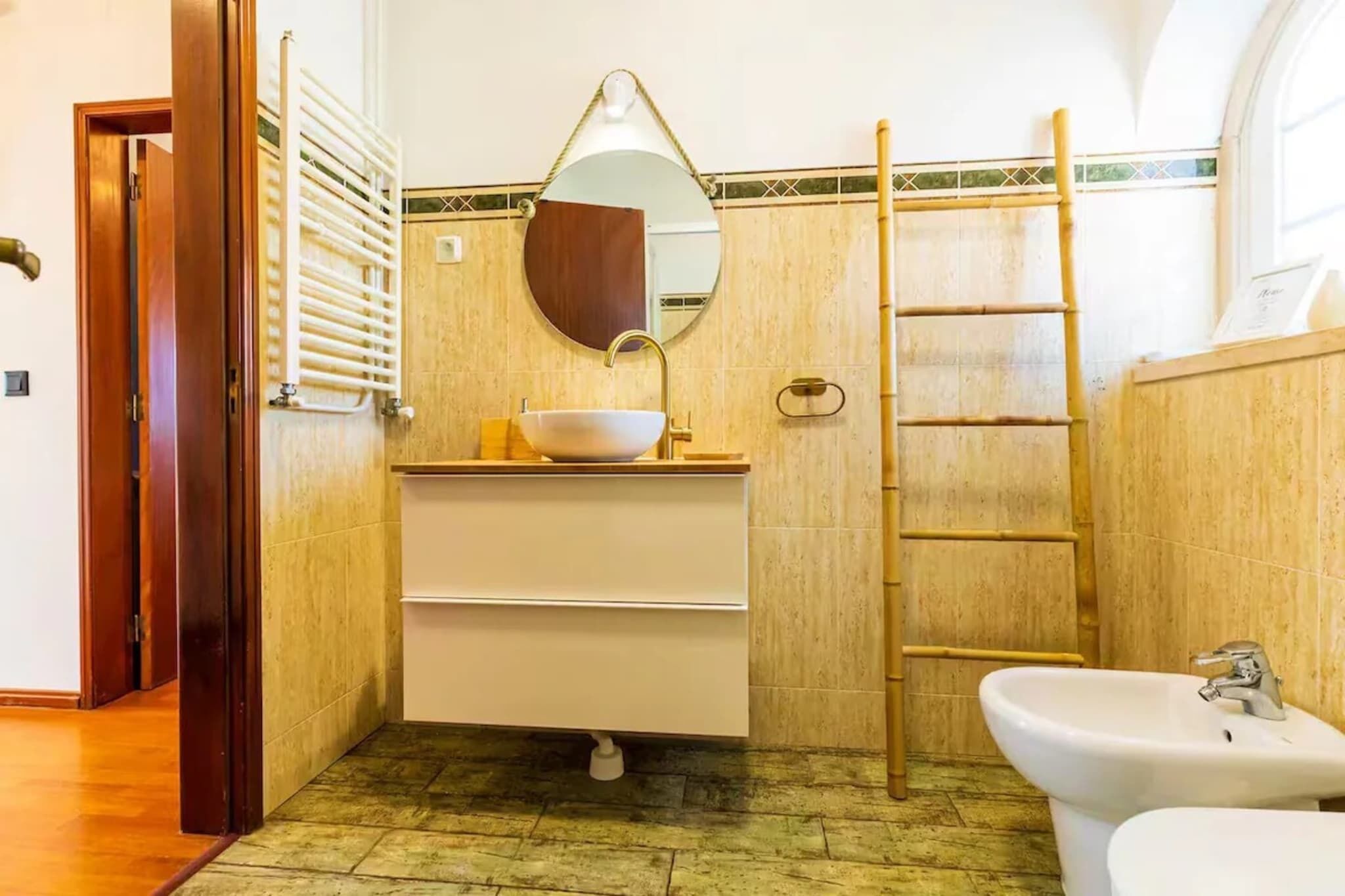 Ein Badezimmer mit Waschbecken, Spiegel, Handtuchhalter und einer Holzleiter.