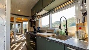 A modern kitchen with a large window, a sink, and a countertop. - Quinta Maresia Tiny House 2 (Carvoeira)
