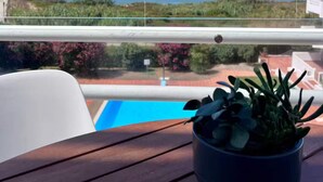 Une table en bois sur laquelle est posée une plante en pot, offrant une vue dégagée sur un ciel bleu azur et la mer.