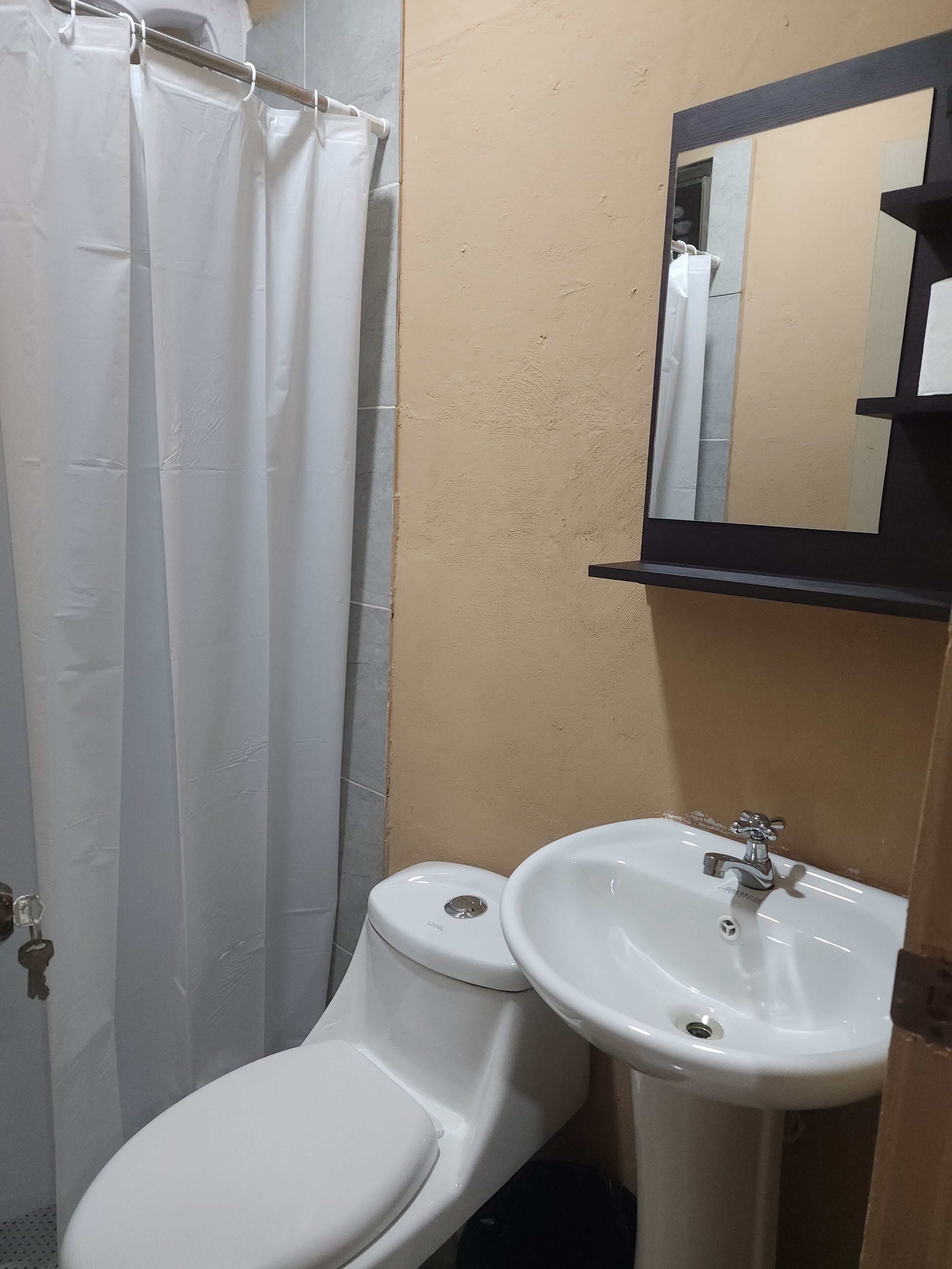Un baño con inodoro, lavamanos y cortina de ducha.