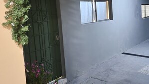 A building with a green door, a small window, and a concrete floor. - Milo's Hostel and Residences  (Santa Ana)
