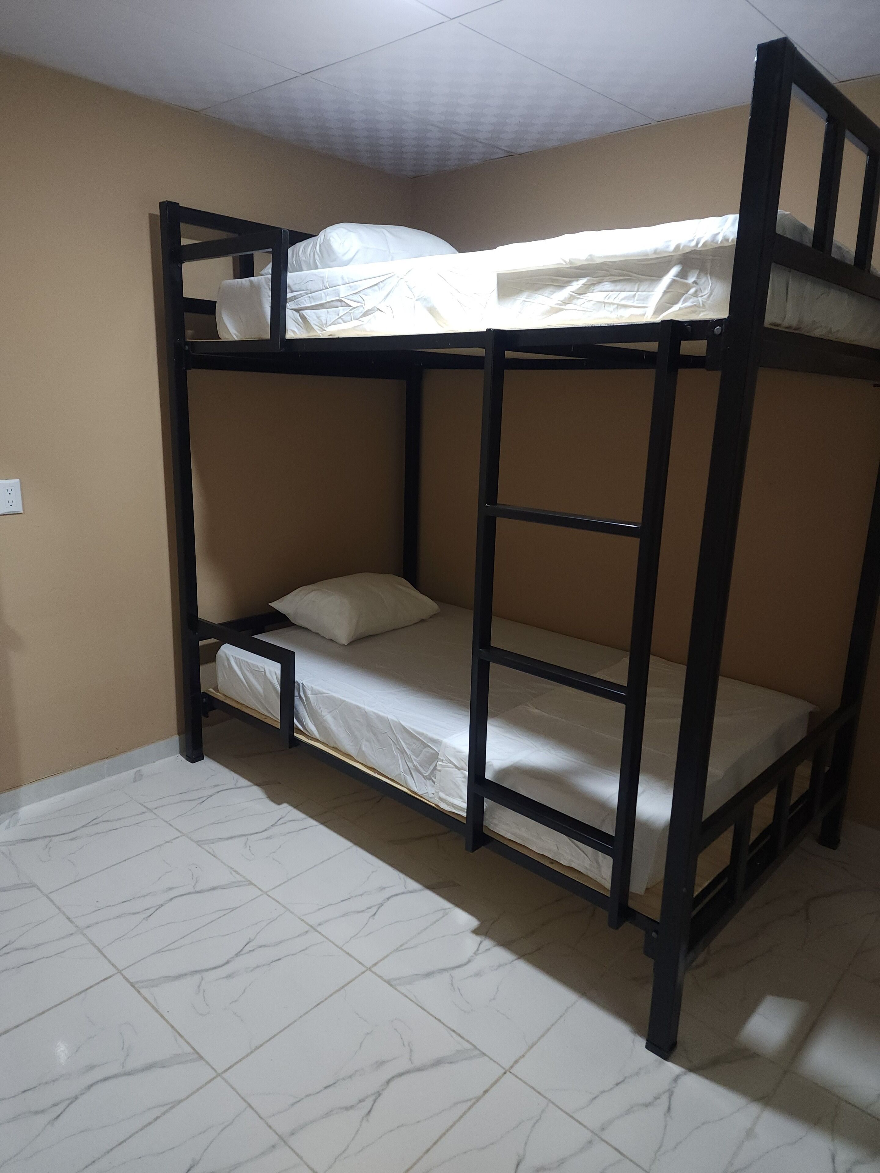 A bunk bed room with a tiled floor and beige walls.