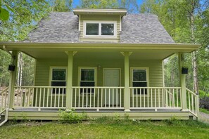A two-story house with a porch, a front door, and two windows. - Clean & Cozy | Pet Friendly Cabin at Hatcher Pass (Palmer)