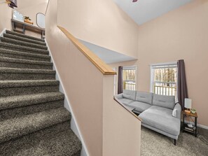 A staircase leading to a living area with a sofa and a window. - Clean & Cozy | Pet Friendly Cabin at Hatcher Pass (Palmer)