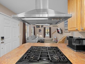 Una cocina con extractor de acero inoxidable, encimera de granito y un comedor con sofá y mesa de centro.