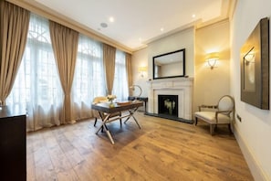 A room with a fireplace, a desk, and a chair. - Royal Mayfair Villa (London)