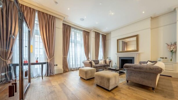A spacious living room with a fireplace, two sofas, and a glass partition. - Royal Mayfair Villa (London)
