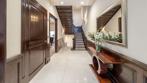 A hallway with a wooden door, a staircase, and a console table with a vase. - Royal Mayfair Villa (London)