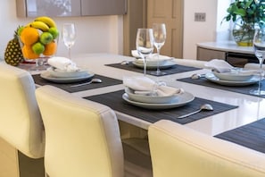 A dining table set with plates, glasses, and cutlery, with chairs around it. - Royal Mayfair Villa (London)