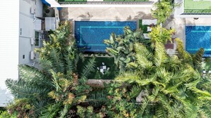 Edificio residencial con piscina rodeada de abundante vegetación.