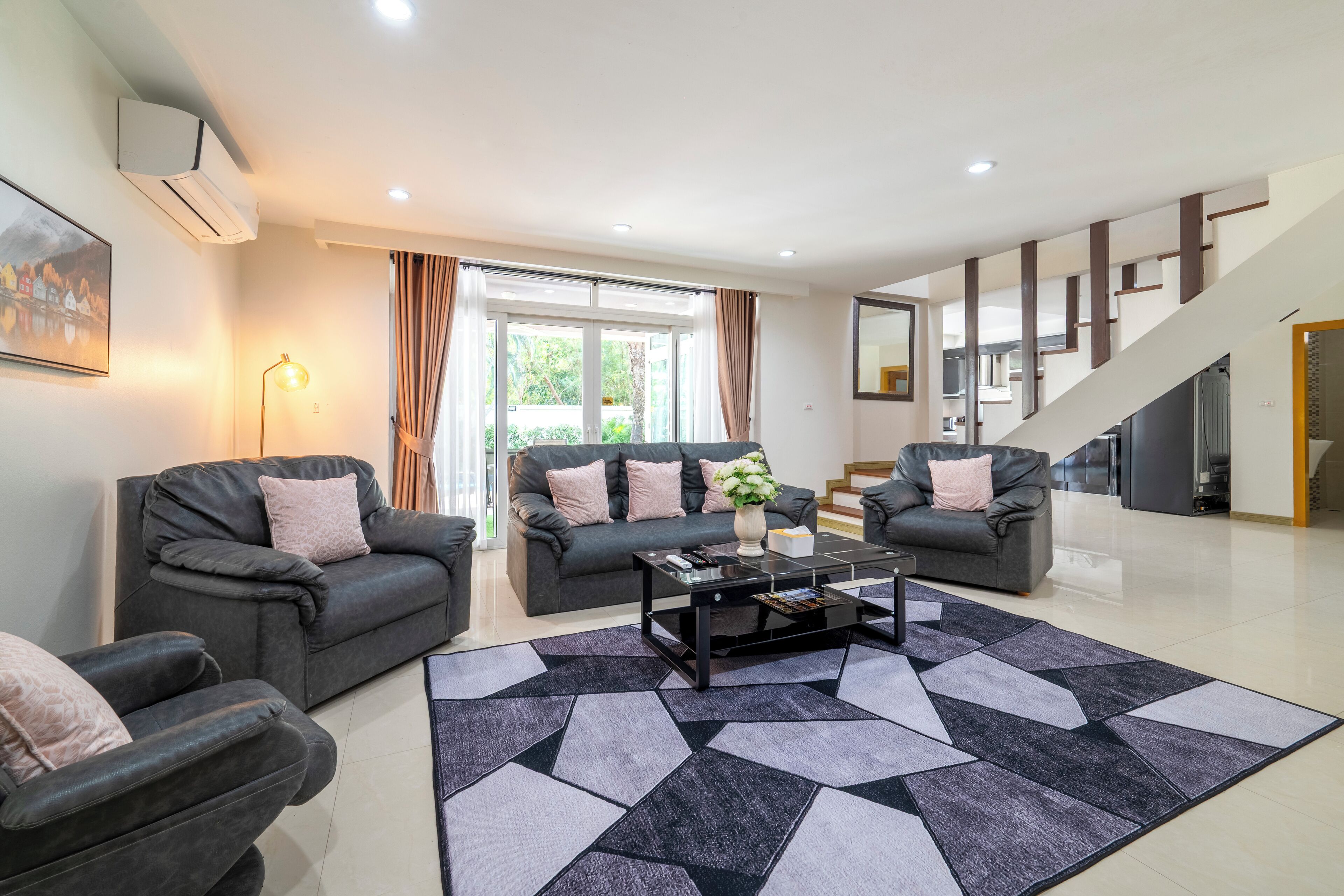 A modern living room with two sofas, a coffee table, and a patterned rug.