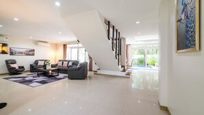 Amplia sala de estar con una escalera moderna, un cuadro grande y vistas al exterior.