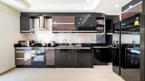 Una cocina moderna con electrodomésticos de acero inoxidable, armarios negros y una vinera empotrada.