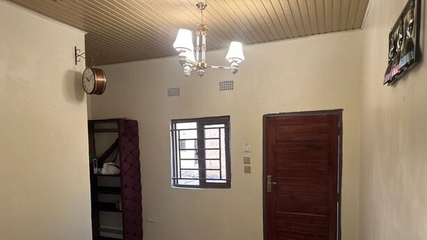 Un dormitorio con cama, armario, ventana, puerta y una araña.