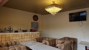 Un comedor con candelabro, televisor y salpicadero de azulejos.