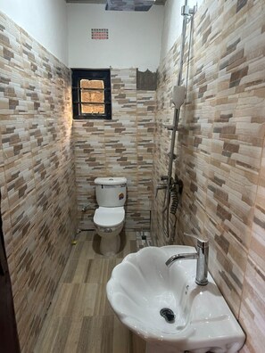 A bathroom with a tiled wall, a sink, and two toilets. - infinity 555 lodge (Lusaka)