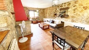 Una sala de estar rústica con pared de piedra, pared de acento roja, mesa de comedor de madera y sofá blanco.