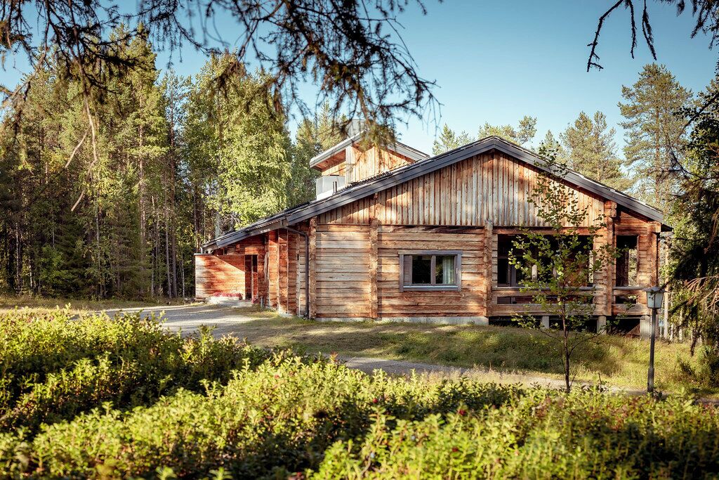 A rustic cabin with a sloped roof, wooden exterior, and a small porch.