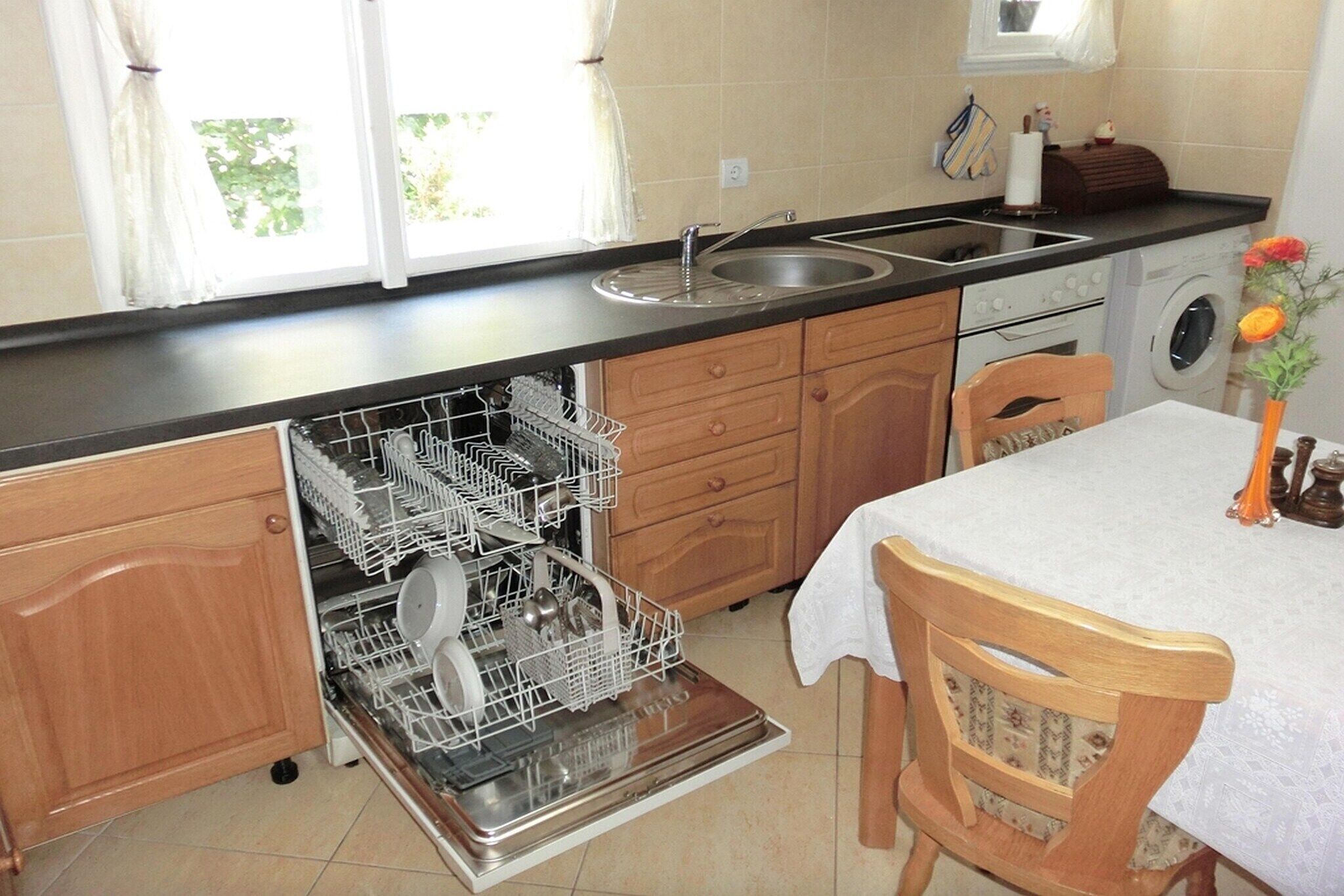 Una cocina compacta con lavavajillas, lavamanos y lavadora.