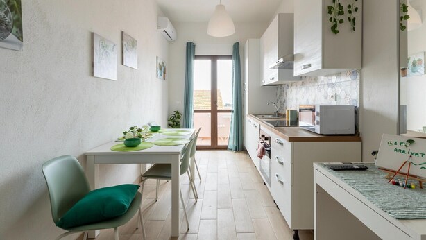 Een compacte keuken met een eethoek, een klein barretje en uitzicht naar buiten.