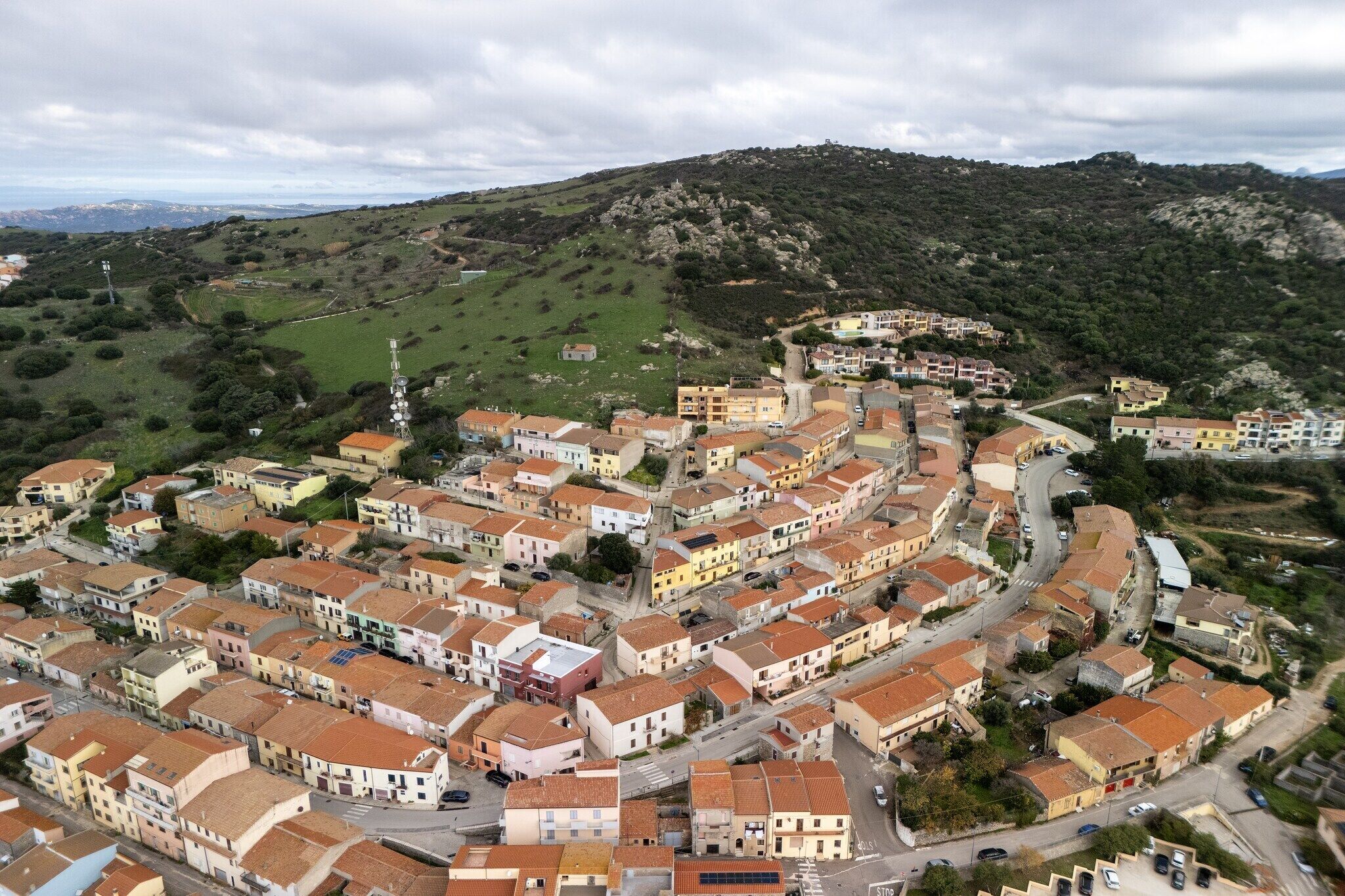 Una cittadina con edifici addossati, strade tortuose e una collina sullo sfondo.