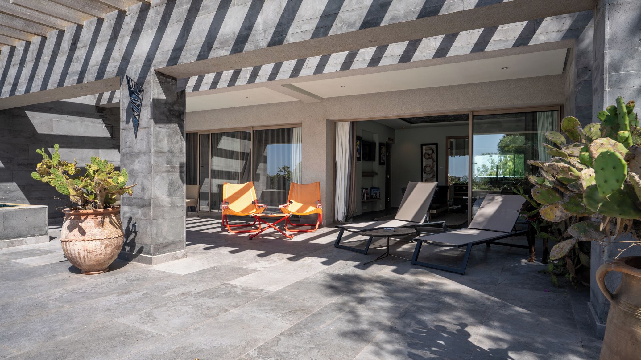 Un bâtiment moderne doté d’un patio aménagé avec des espaces de détente en plein air et un grand cactus.