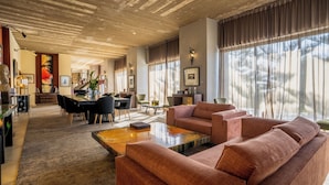 Amplia sala de estar con un sofá grande, una mesa de centro y un comedor con un piano.