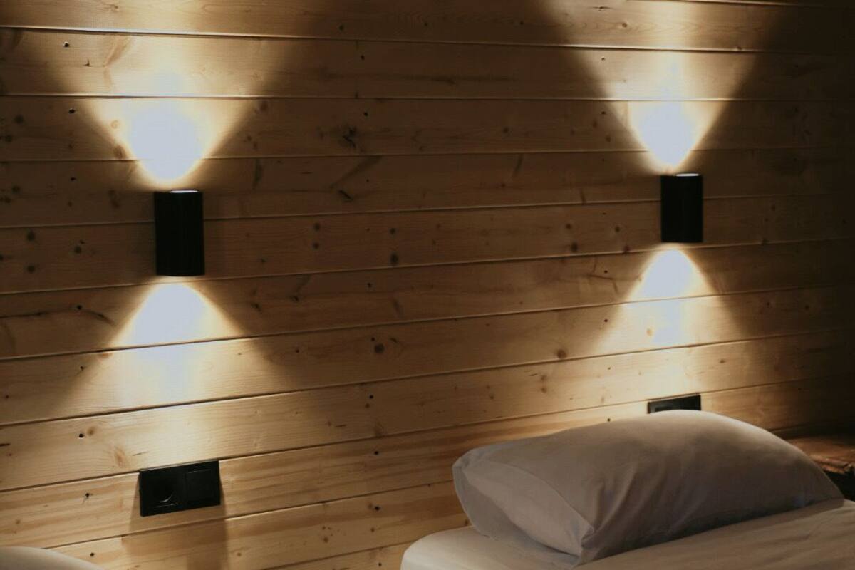 Habitación con paneles de madera, dos camas e iluminación en la pared.