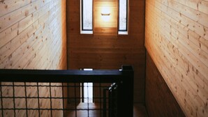 A narrow wooden corridor with two vertical windows allowing natural light to enter. - Ranch In Variani (Variani)