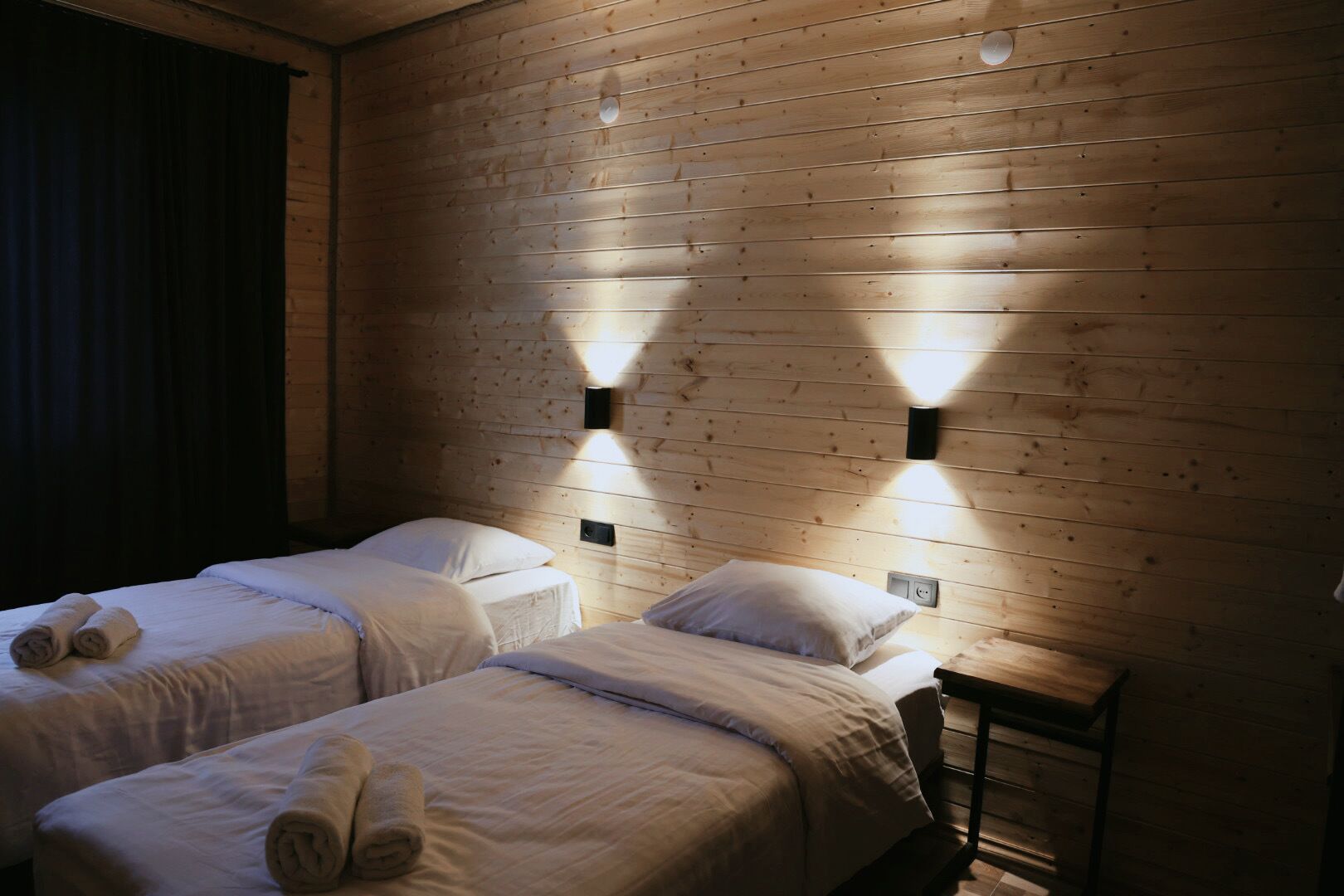 Ein Zimmer mit zwei Betten, Holzwänden und Wandleuchten.
