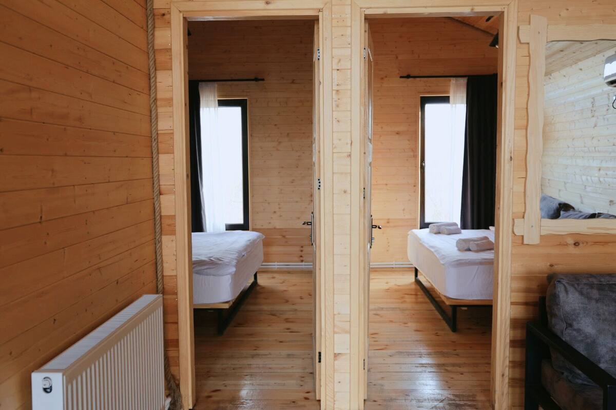 Una cabaña de madera con dos camas, un radiador y una ventana.