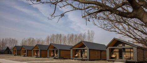 A row of modern log cabin-style cabins with large windows and outdoor seating areas.