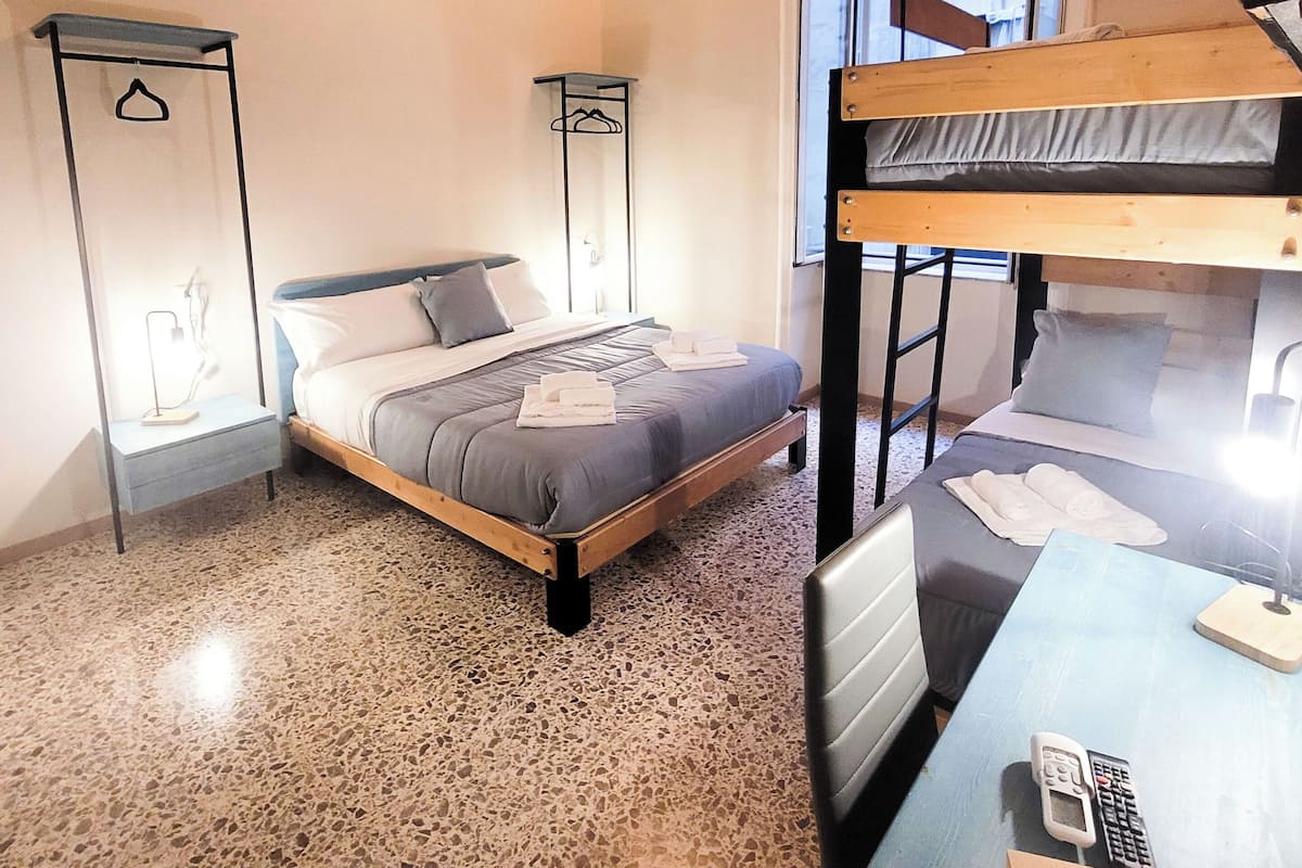 Ein Zimmer mit einem Bett, einem Schreibtisch mit Telefon, einem Fenster und einem Stockbett.