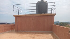 Een terras op het dak, met een waterreservoir, een metalen reling en uitzicht op het landschap.