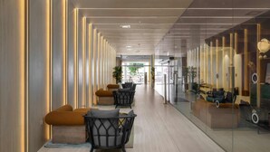 A modern hotel lobby with a central seating area, glass partitions, and a view into the adjacent room. - By Edomlux סטודיו מודרנית במתחם סי סייד 100 מטר מהים (Eilat)
