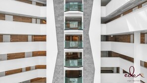Ein modernes Mehrstöckhaus mit Balkonen, ausgestattet mit Glasgeländern und Holzverkleidungen.