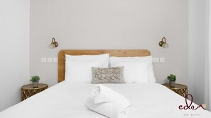 A neatly made bed with white linens, two bedside tables with gold accents, and decorative wall sconces. - דירה משפחתית מעוצבת בסי סייד עם בריכה מחוממת - By Edomlux (Eilat)