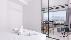 Ett modernt hotellrum med en stor säng, en balkong med utsikt och en vägg av glas.