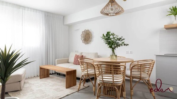 Un salon moderne avec une table de salle à manger ronde, des chaises en osier, un canapé et une table basse.