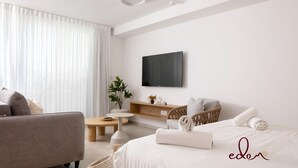 Una habitación de hotel moderna con una cama, un sofá, una mesita, un televisor y una planta.