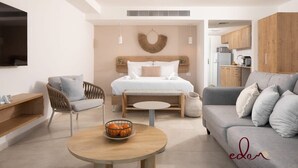 Una habitación de hotel moderna con cama, sofá, mesa de comedor y zona de cocina.